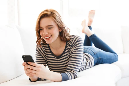 Frau bedient ihre Beschattung mit dem Smartphone auf dem Sofa