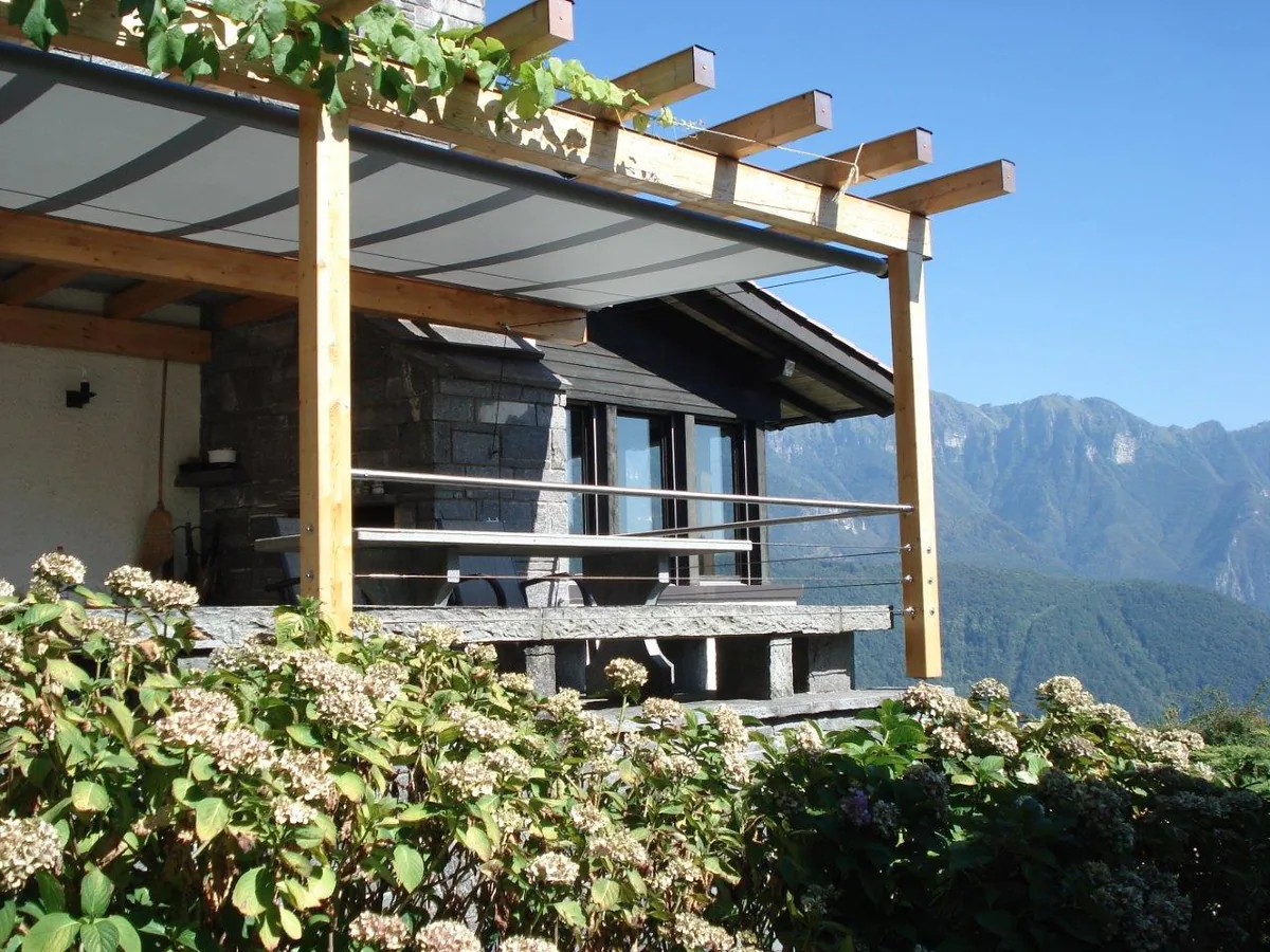 SHADE STRUCTURE als Beschattung einer Holzpergola an einem Berghaus mit Alpenpanorama